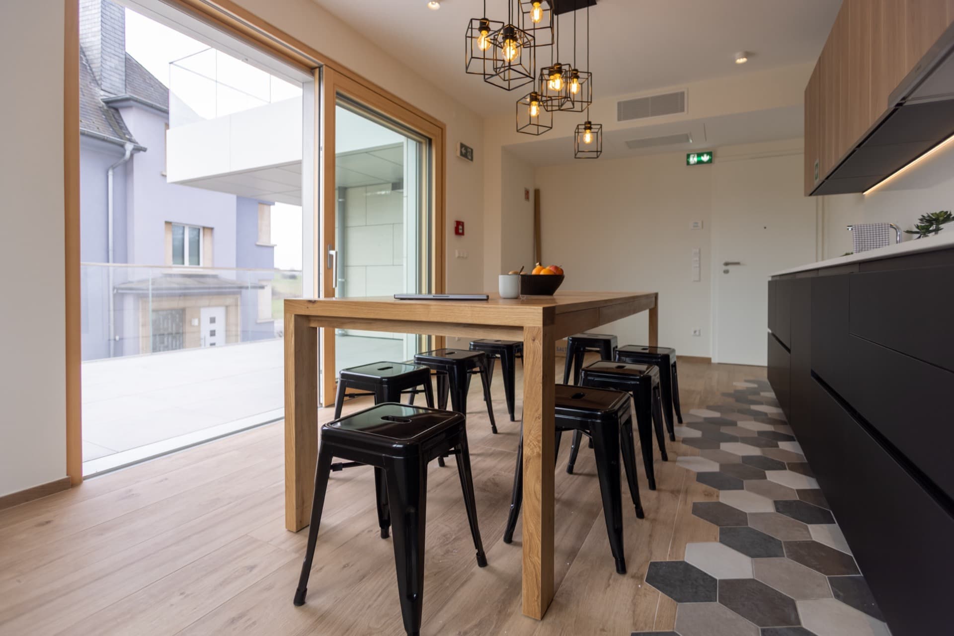 Open kitchen with terrace area. Tall table and chairs, a big hallway, and a large terrace in front of the table.