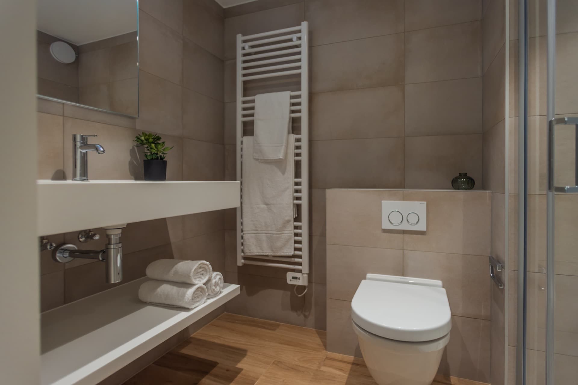 Close-up image of the en-suite bathroom of the bedroom for rent. It depicts a toilet, a sink with a mirror above, and a heating radiator.
Toiletries and towels are provided