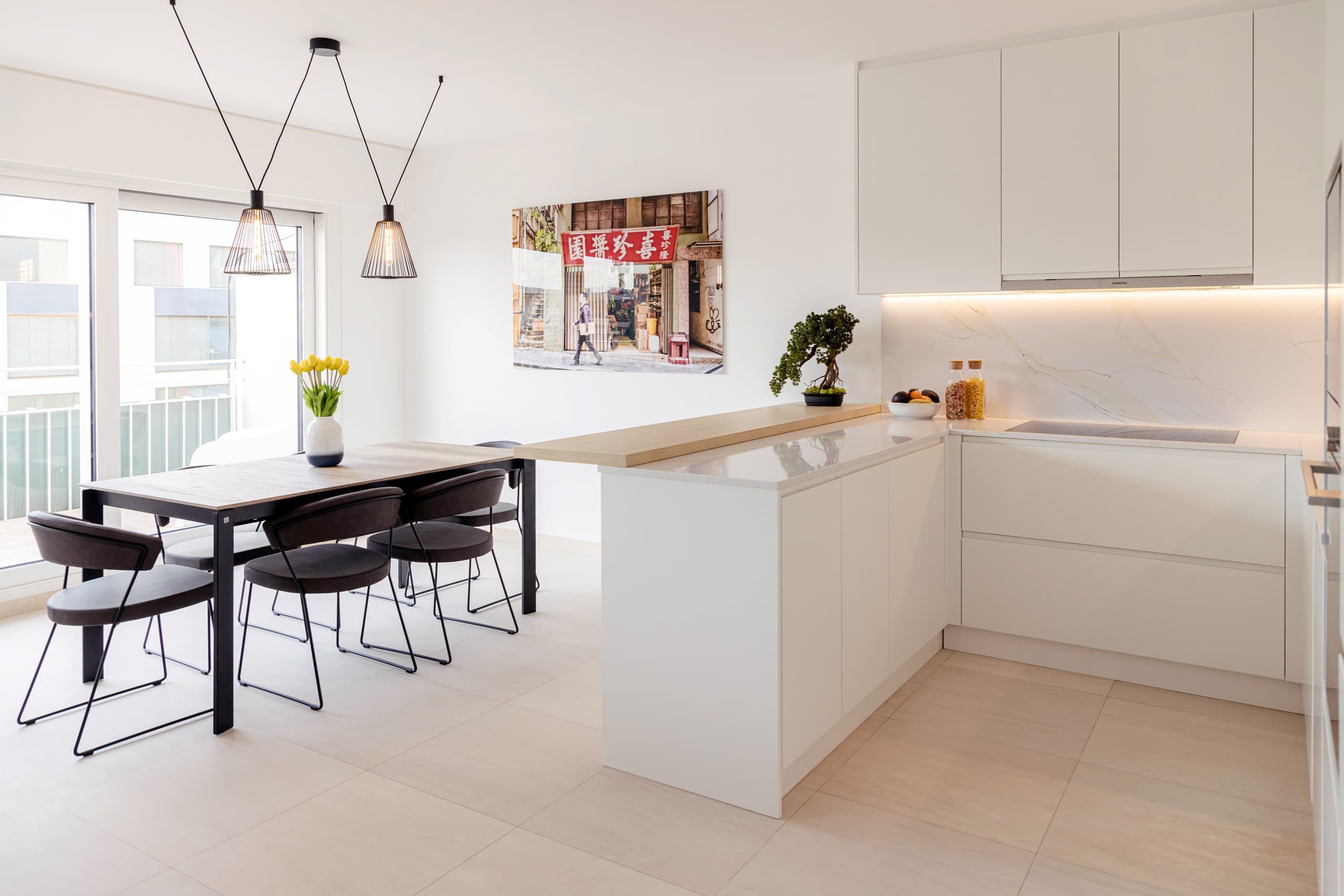 Dining room and kitchen of Apartment Alzette at Hamilius Apartments showing a bonsai tree and a picture of hong kong on the wall