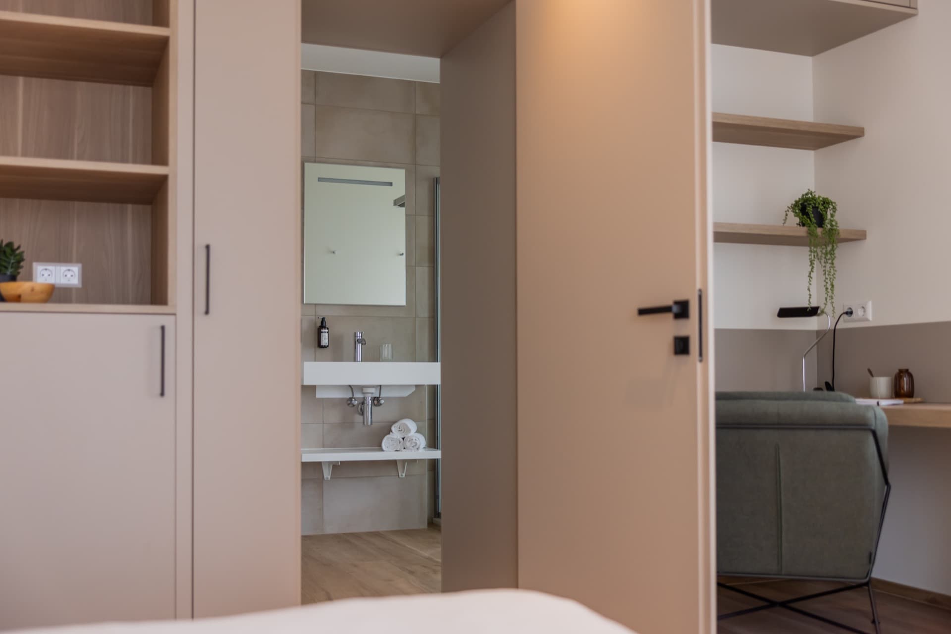 Overview of the bedroom with the en-suite bathroom. The picture depicts the bed, working area, and the en-suite bathroom.
Towels and toiletries are visible in the bathroom