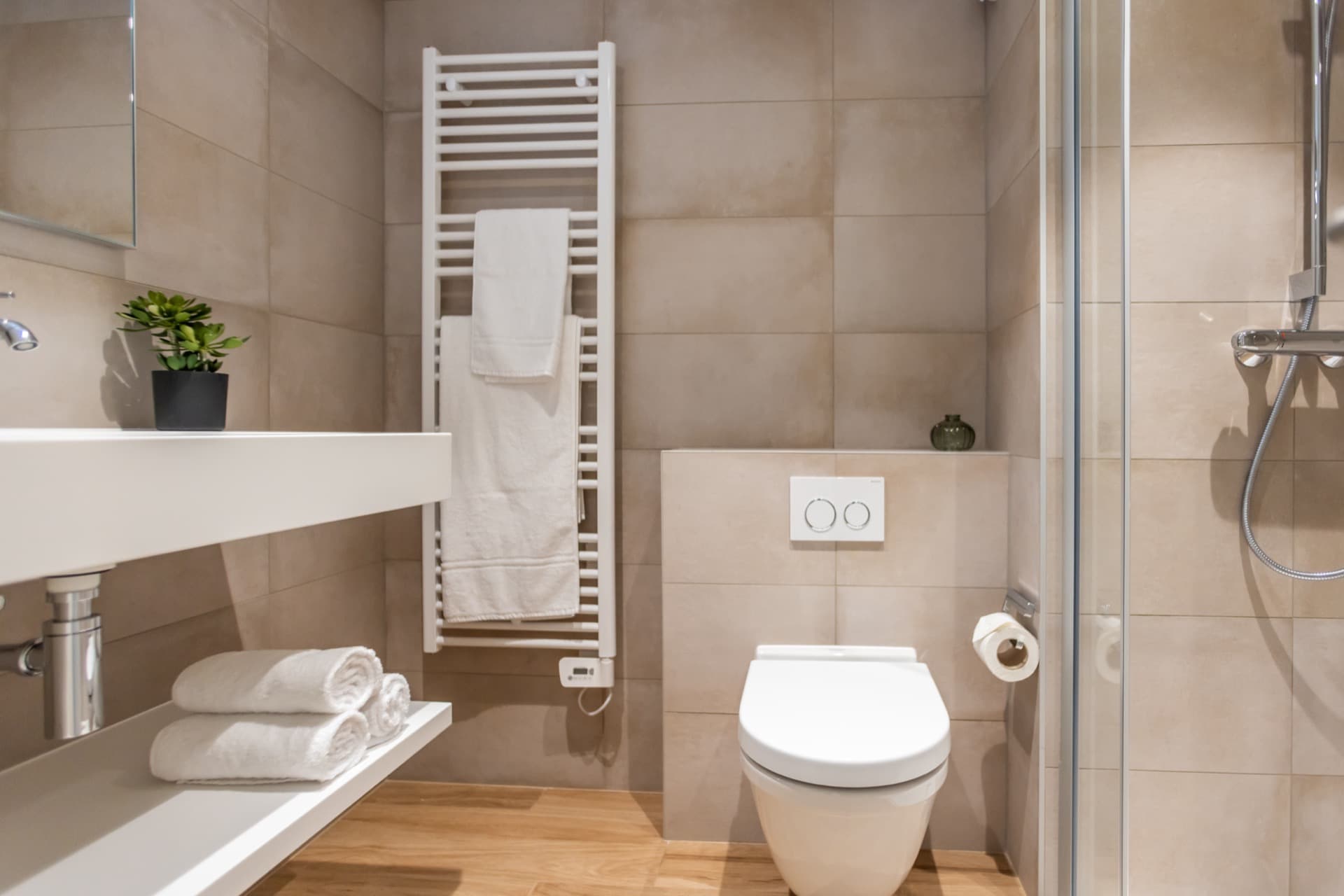 The picture shows another angle of the en-suite bathroom of a furnished bedroom to rent. It depicts a toilet, a sink with a mirror above, a heating radiator and a large floor-to-ceiling window.
Towels and toiletries are provided