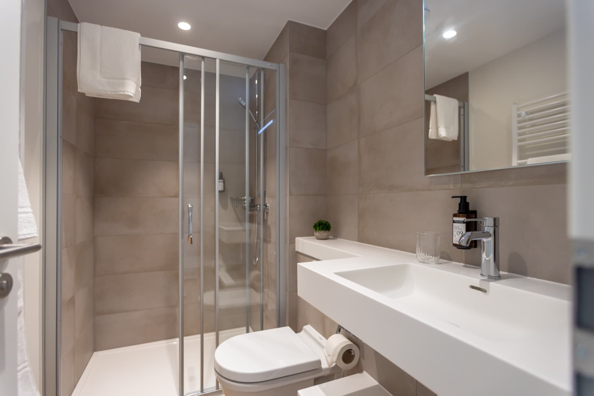 The picture depicts the en-suite bathroom of the room. It has a walk-in shower, a sink, and a mirror above it.
Toiletries and towels are provided.