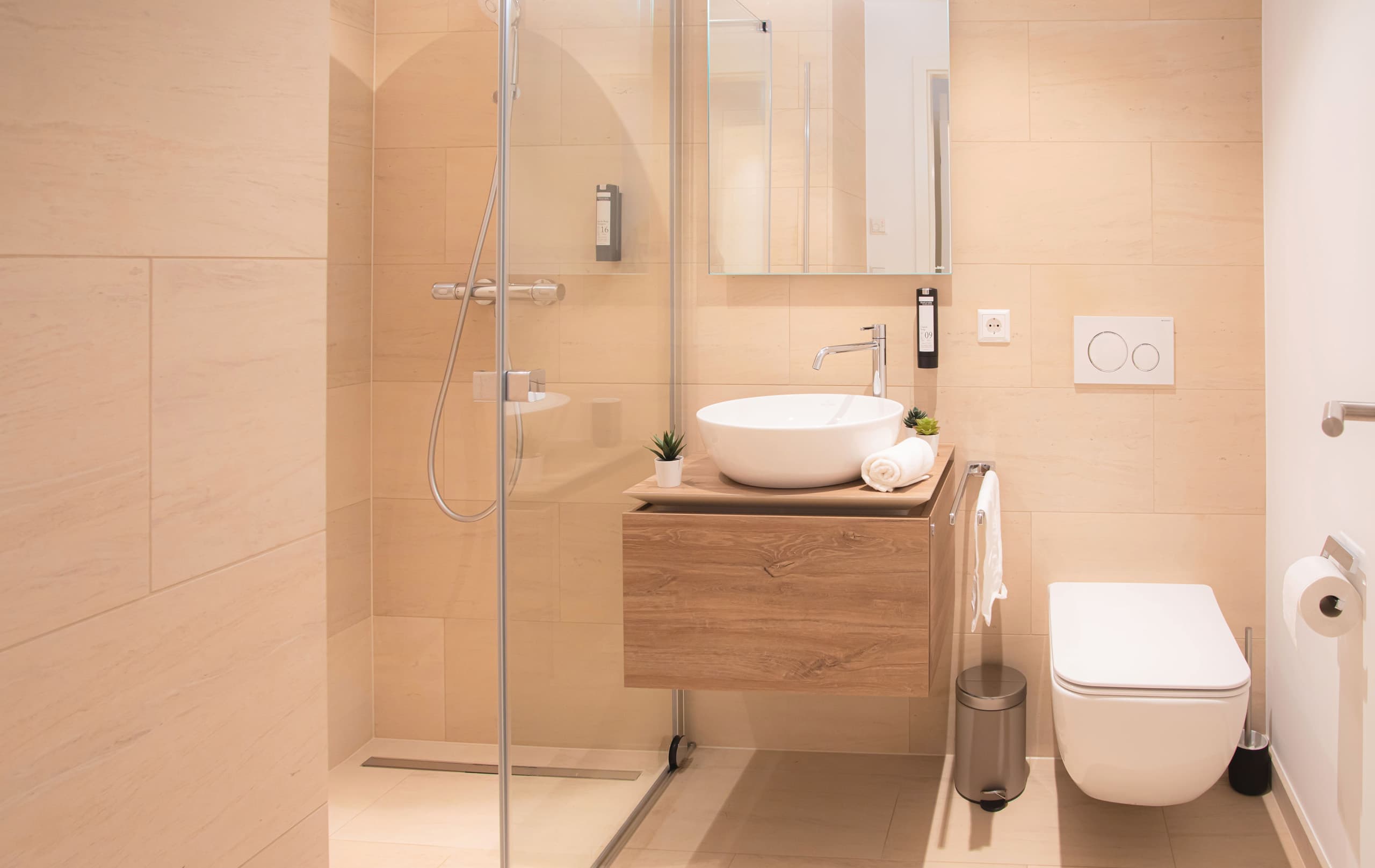 Bathroom with shower cabin, toilet, and white sink. Soap and towels are provided.