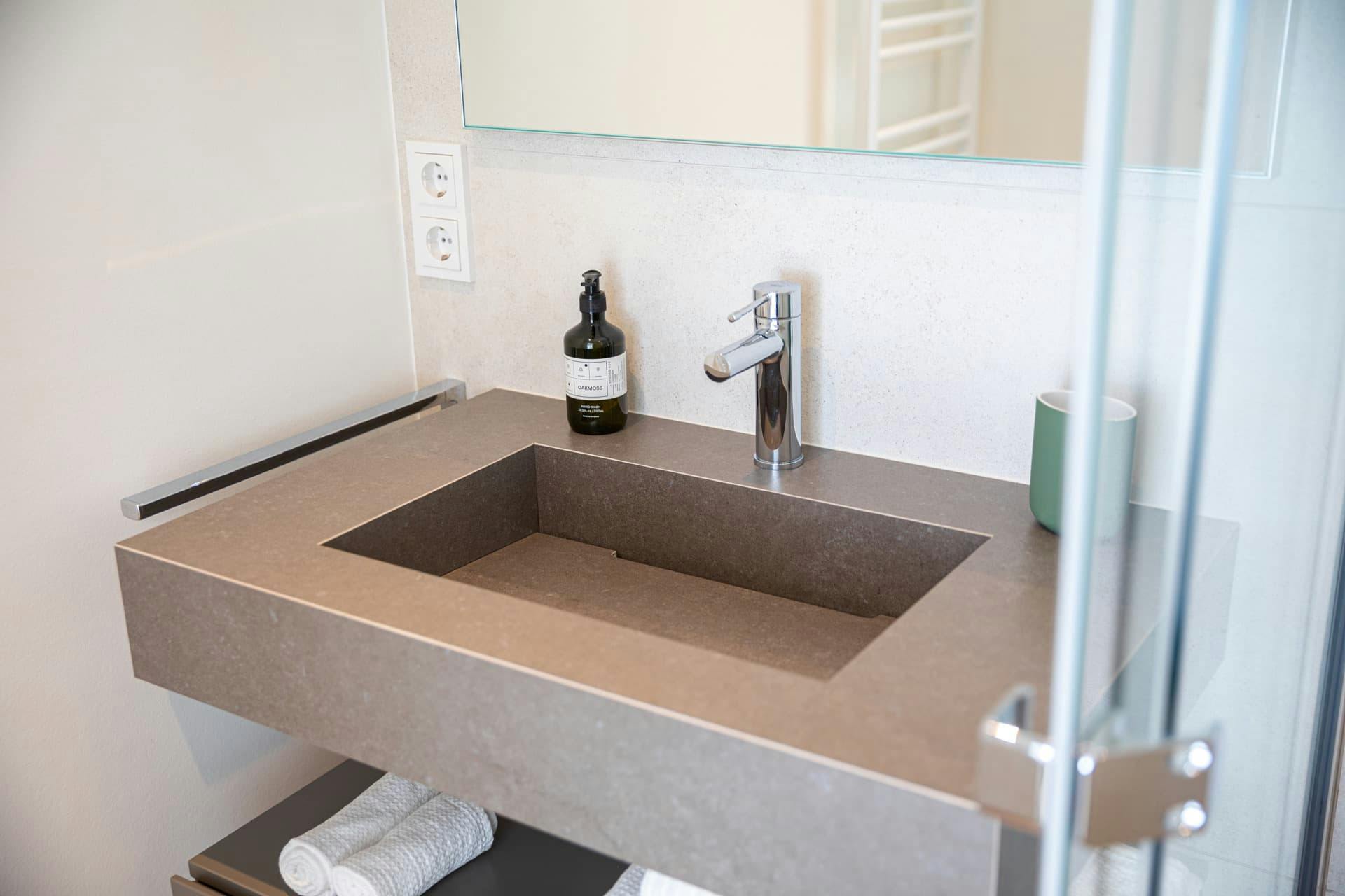 Picture of modern sink with fancy soap and toothbrush holder. The left side features an electric socket.