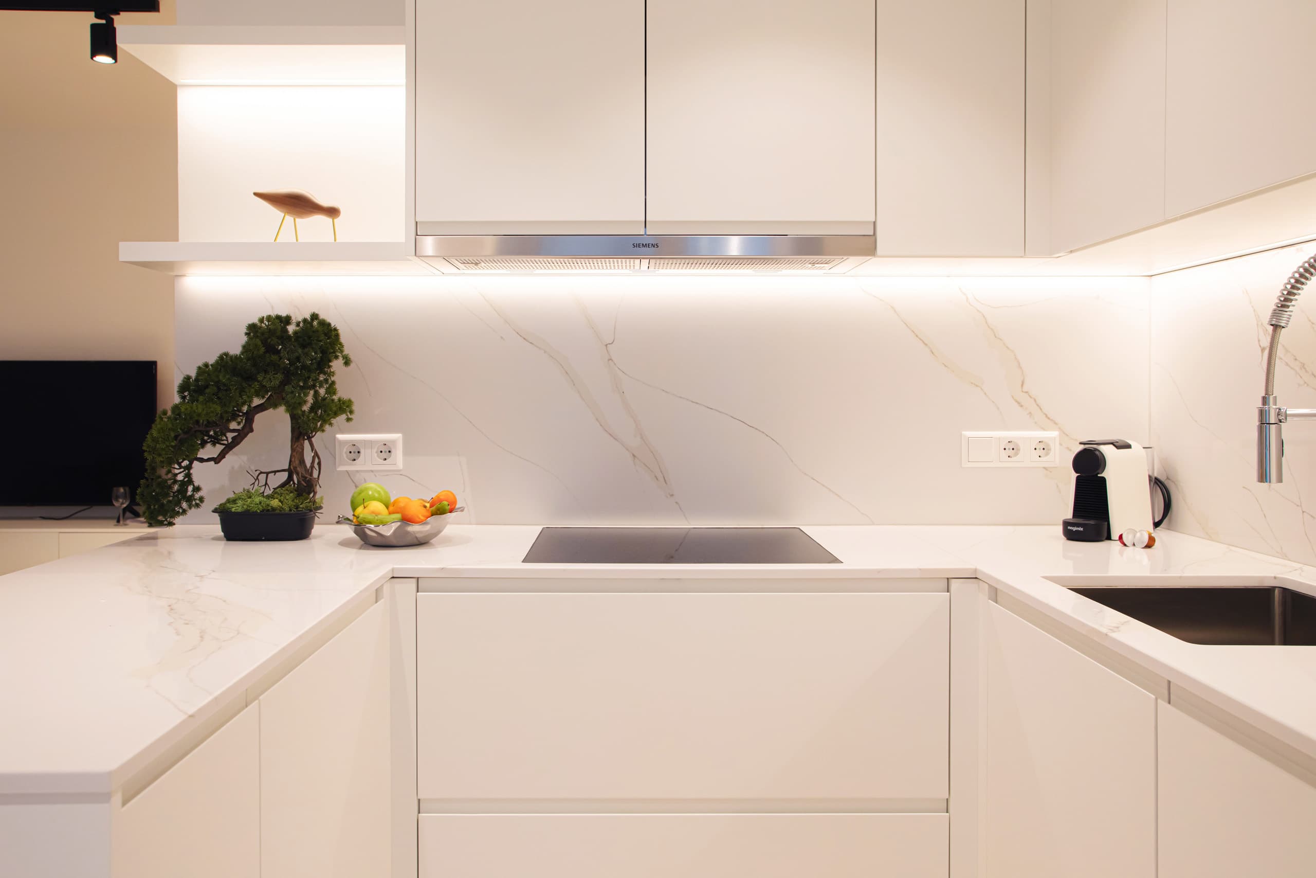 Kitchen of Apartment Eisch at Hamilius Apartments showing a bonsai tree, stove and a bowl of fruit.  The kitchen has a marble top and backsplash