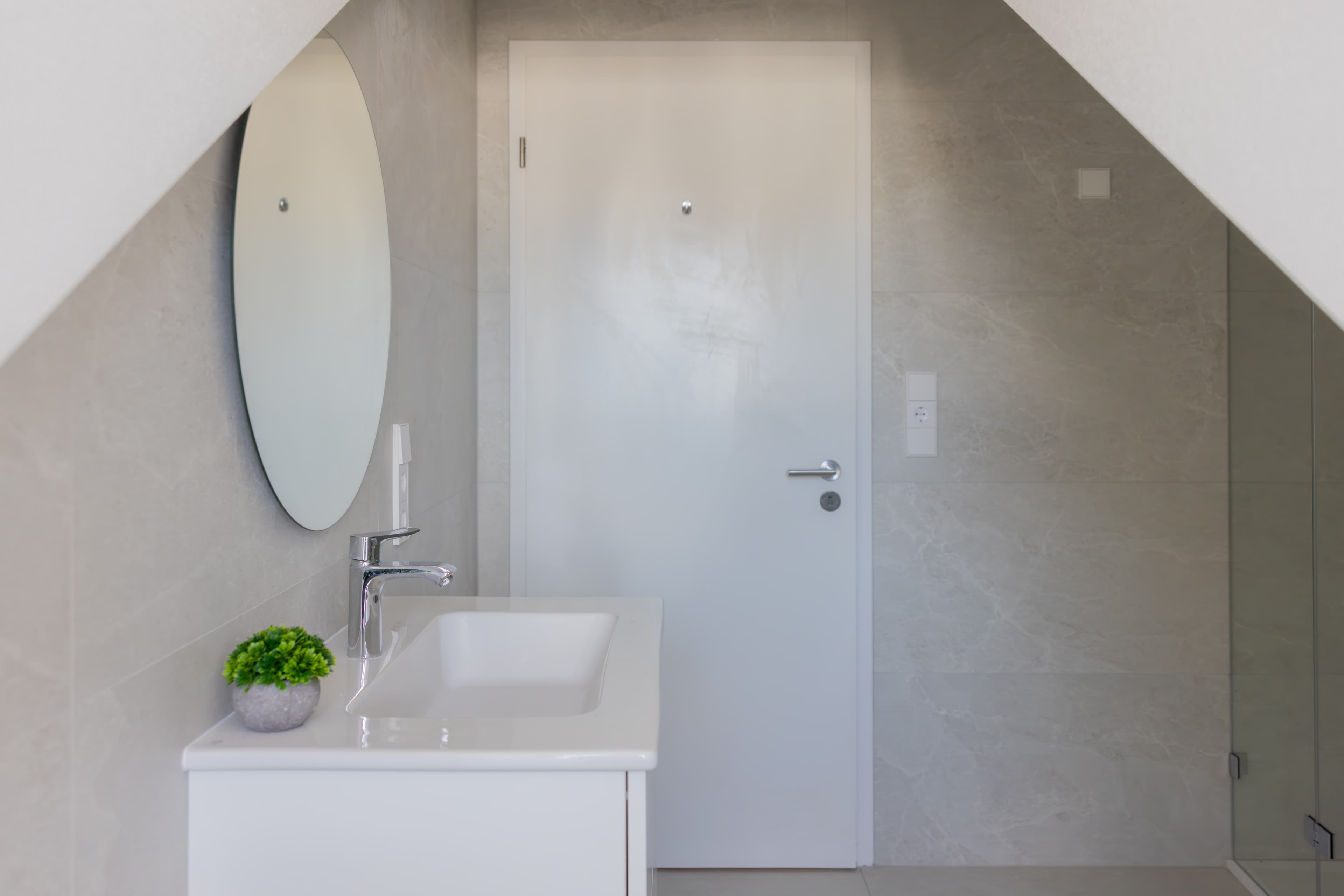 The picture depicts a white sink with a mirror above.